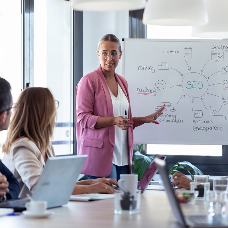 young-businesswoman-pointing-at-white-blackboard-a-NU2N2WV young-businesswoman-pointing-at-white-blackboard-a-NU2N2WV