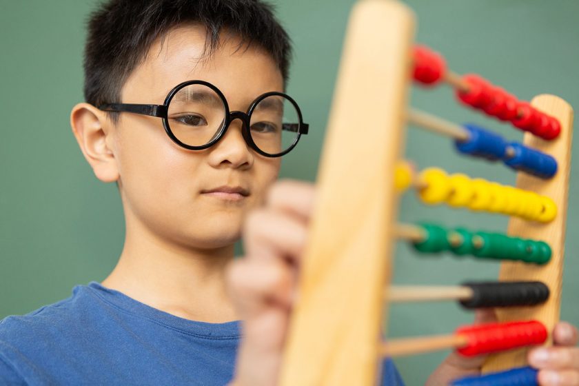 boy-learning-math-with-abacus-in-a-classroom-at-DE9N3LX-min