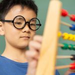 boy-learning-math-with-abacus-in-a-classroom-at-DE9N3LX-min
