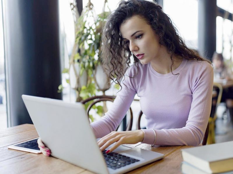 Young woman working on laptop in coffee shop Young attractive woman working on laptop in coffee shop